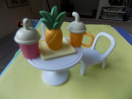 Barbie sized 2 white chairs, white bistro table, pineapple on tray, 2 drinks with handles