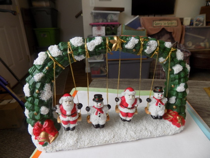 9  inch wide ceramic 2 Santas and 2 Snowmen on swings with an arch over them, snow around