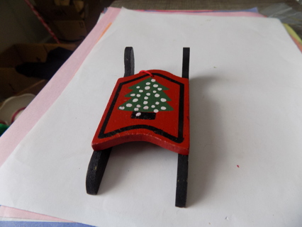 Red and black wood sled ornament has polka dot tree painted on it