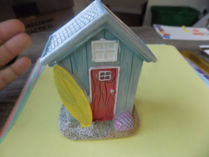 4 nch resin beach shack blue with red door and a yellow surfboard