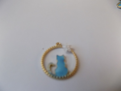 Blue enamel cat charm sitting inside goldtone circle with white flower on rim
