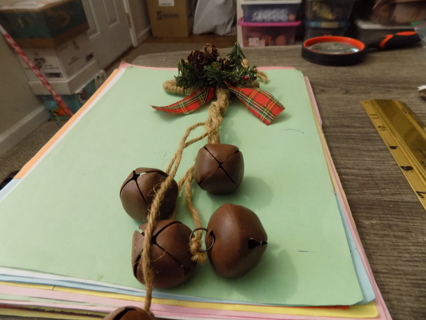 Jute and rustic jingle bell door knob decoration accented pine cones, and red plaid bow