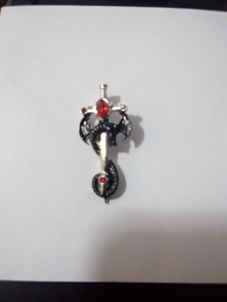 Silver cross with black wings and red jem over  stainless steel 