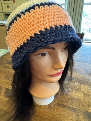 Qty of 1 Crocheted Hats. Colors are Navy Blue, Peach, Off White, and light mixed Blue etc.