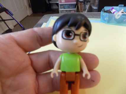 Ryans  World 3 inch pvc boy doll wears glasses, black hair, green shirt, brown pants orange shoes