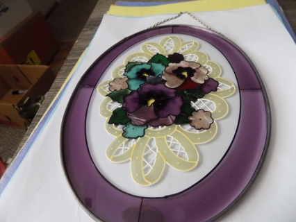 8 inch tall oval stained glass suncatcher has pansies and lace backing with 1 1/2 purple rim