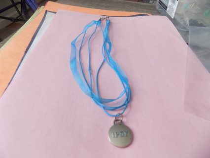 Necklace on blue organdy ribbon & blue cord has silverstone Epsy round charm dangle