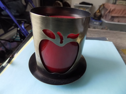 Brass candle holder with apple shape cut out on bowl shape base red, candle inside