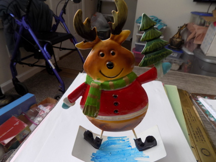 Metal 8 inch reindeer holds a tree in his hand and on a rocker base