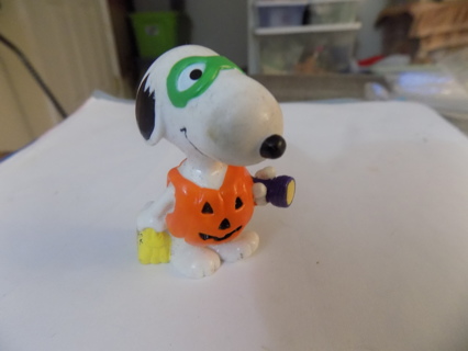 Snoopy of Peanuts comics in Halloween costume green mask, pumpkin suit flashlight