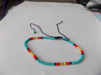 Adjustable bracelet E Beads mostly aqua, red, yellow,clear on black cord