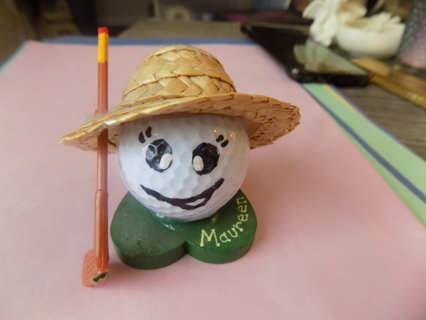 whimsical golf ball ornament wears straw hat painted on fire. Holds a club on heart base