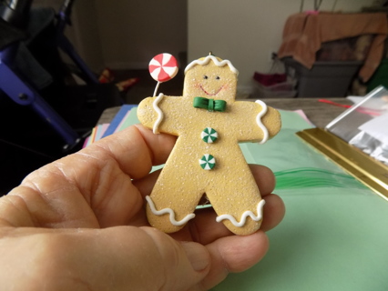 3 inch tan gingerbread boy ornament holds red and white lollipop, green peppermint buttons