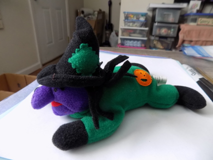 7 inch long witch plush in green outfit, purple face, crawling pose