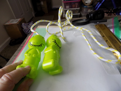 Yellow and white jump rope with green dinosaur handles