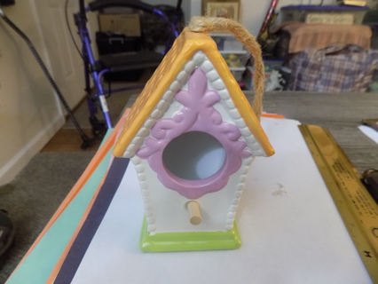 5 inch tall ceramic bird house has orange roof, pink around door green base jute string hanger