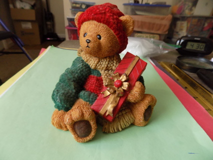 Resin textured bear in red knit hat, green sweater holds red & green present