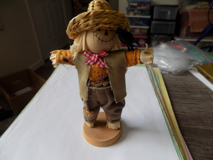 7 inch scarecrow on wood base with crow on  his arms and wears straw hat