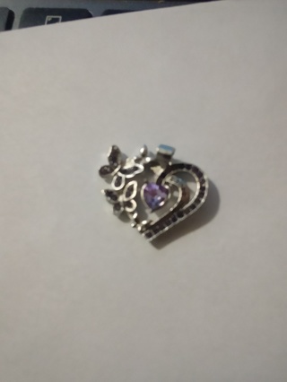 Silver heart with purple heart jem in center over stainless steel 