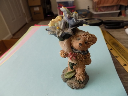 4 inch tall resin textured teddybear holds long bouquet of yellow blue flowers 