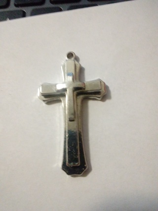 Silver cross with small silver cross in center over stainless steel 