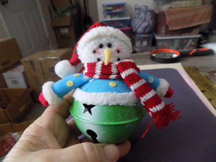 Green metal jingle bell with snowmen plush on top in blue jacket