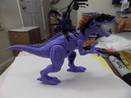 Purple and black dinosaur with orange fins on tail