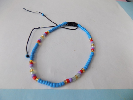 Adjustable mostly blue E bead bracelet, on black cord few red ones purple, yellow green